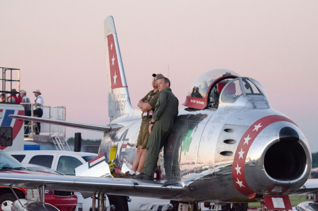 Men standing on wing of airplane.